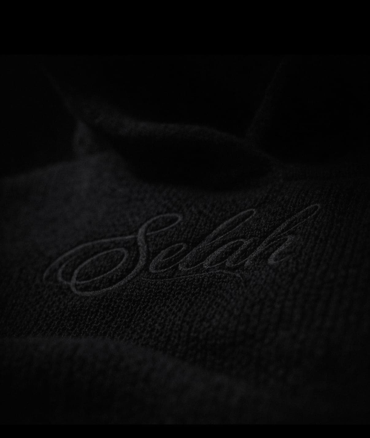 Tonal black-on-black Selah script embroidered on knit